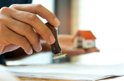 Close-up rubber stamp and model house in hand,Concept image of home mortgage business.