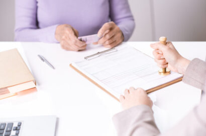 Close-up of unrecognizable specialist stamping paper while certifying it for senior lady